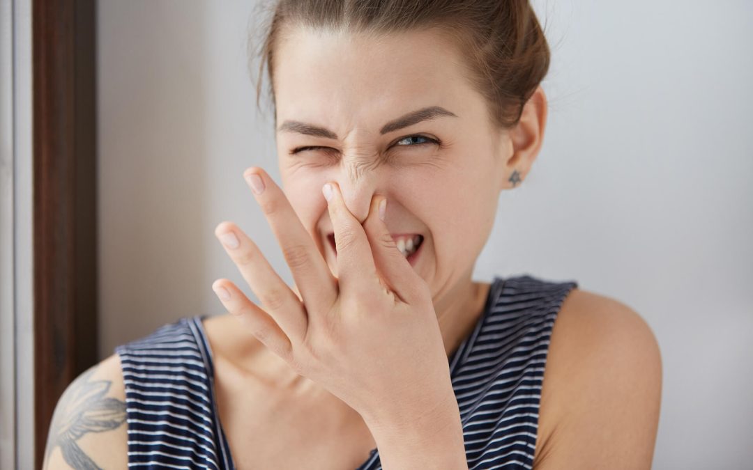 Woman holding her nose in response to strange odors in the home.